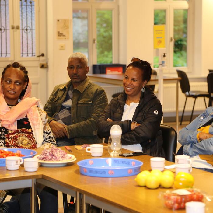 Mensen met een migratieachtergrond samen aan een tafel met gezond voedsel