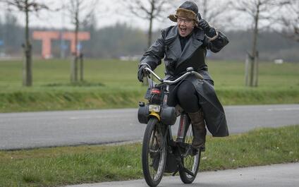 Vrouw in zwarte jas op oude motorfiets
