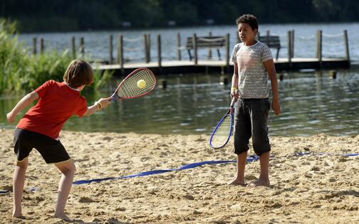 twee kinderen die spelen met een racket op het strand