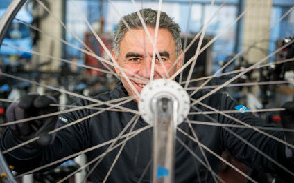 close-up van lachende man die doorheen de spaken van een fiets kijkt
